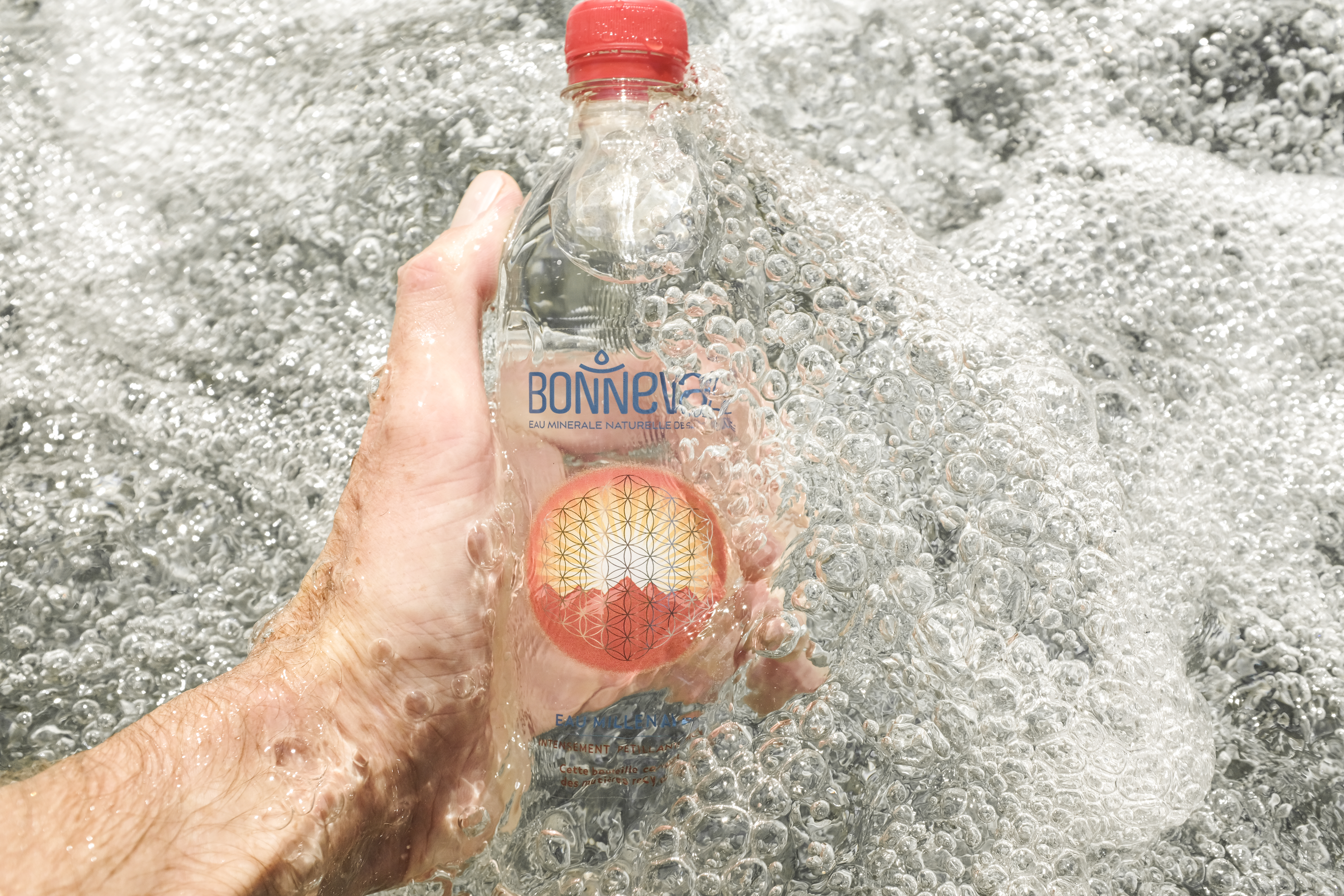 « Main tenant une bouteille d’eau pétillante plongée dans un ruisseau au courant vif
