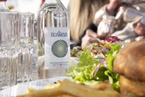 Bouteille d’eau minérale naturelle Bonneval servie à table avec un repas équilibré en extérieur