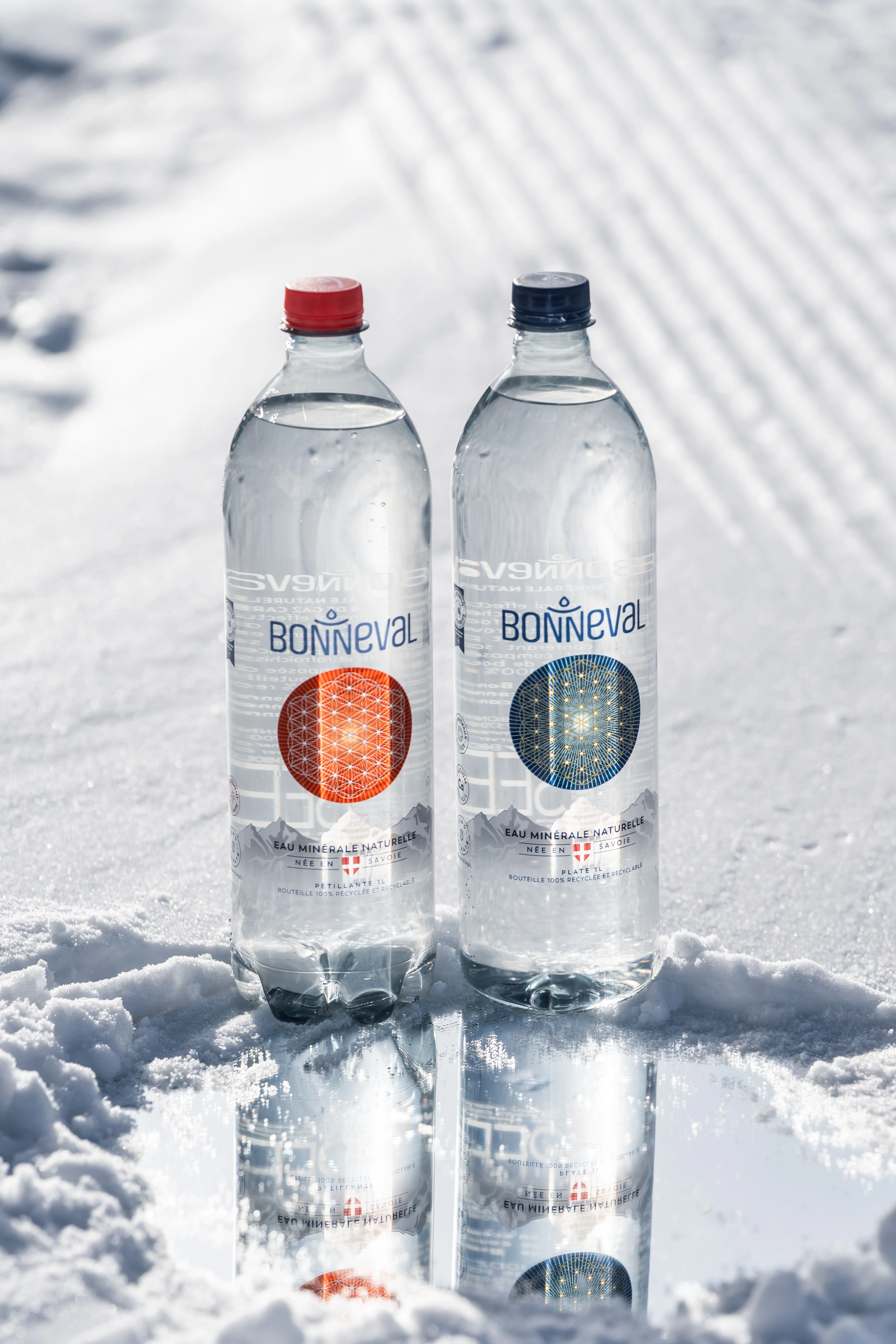 Deux bouteilles d’eau minérale Bonneval (plate et pétillante) posées sur la neige en montagne